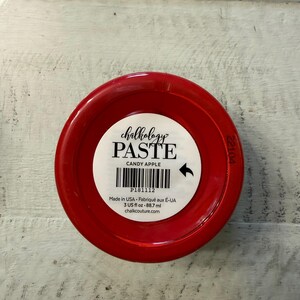 May include: A round red container of Chalkology Paste in the color Candy Apple. The white label features the text Chalkology PASTE, CANDY APPLE, a barcode, P181112, Made in USA, 3 US fl oz, 88.7 ml, and the website chalkcouture.com.