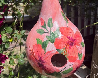 Casita para pájaros con forma de calabaza color melocotón, adornada con flores de hibisco color melocotón y colibríes.