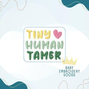 May include: A light blue and green embroidered patch with the text "Tiny Human Tamer" and a pink heart. The patch is surrounded by a white border with a blue dotted line. The text "Baby Embroidery Goods" is below the patch.