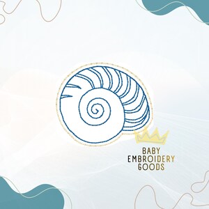 May include: An embroidered seashell design in white with blue stitching and a gold outline. The design is on a light background with the text "BABY EMBROIDERY GOODS" and a gold crown.