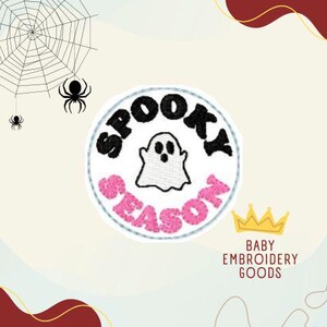 Op de afbeelding: Een witte cirkel met de woorden "Spooky Season" in zwarte en roze letters. Een witte geest met zwarte ogen bevindt zich in het midden van de cirkel.