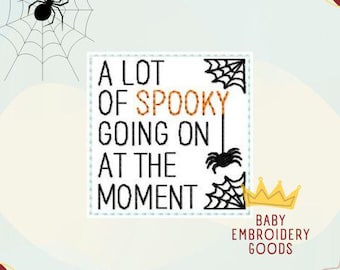 May include: A white square with black text that reads "A lot of spooky going on at the moment". There is a black spider with a web in the upper left corner and a black spider with a web in the lower right corner. The text "Baby Embroidery Goods" is in the lower right corner.
