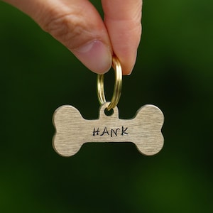 May include: Gold bone-shaped dog tag with the name "HANK" engraved on it.