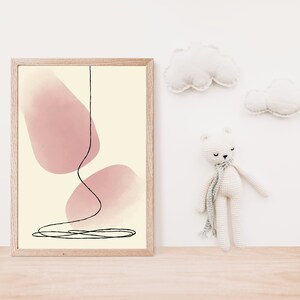 May include: A framed print with a minimalist abstract design featuring two pink watercolor shapes and a black line drawing. The print is hanging on a white wall with a white teddy bear and two white clouds.