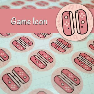 May include: Pink and white game console controller stickers. The stickers are round and feature a pair of controllers with buttons and a pink background.
