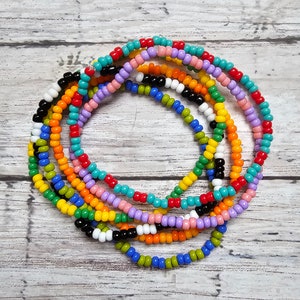 May include: A colorful beaded necklace made of multiple strands of small, round beads in various colors, including red, orange, yellow, green, blue, purple, and white.