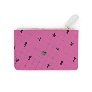 May include: A pink zippered pouch with a repeating pattern of black icons, including keys, crowns, and hearts. The pouch has a white zipper pull and a gold-colored zipper.