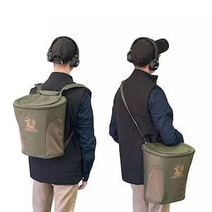 Può includere: Due viste di una borsa verde per la raccolta di funghi Acropolis. La borsa ha una tasca a rete e una patta superiore. Il logo è un fungo. La borsa viene indossata come zaino e come borsa a tracolla. La persona indossa un gilet nero, una camicia blu e un berretto nero.