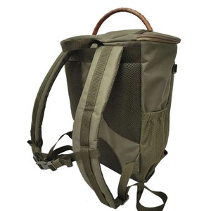 May include: A green canvas backpack with a brown leather handle. The backpack has a mesh pocket on the back and adjustable straps.