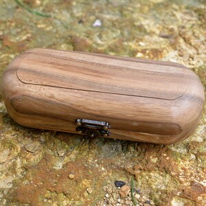 May include: A wooden box with a hinged lid and a metal clasp. The box is made of light brown wood with a natural grain pattern.