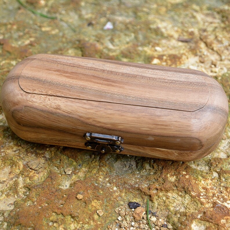 May include: A wooden box with a hinged lid and a metal clasp. The box is made of light brown wood with a natural grain pattern.
