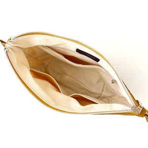 May include: A yellow leather zippered pouch with a white fabric lining. The pouch has multiple pockets inside.