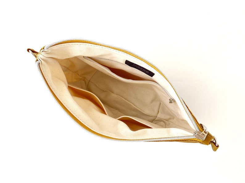 May include: A yellow leather zippered pouch with a white fabric lining. The pouch has multiple pockets inside.