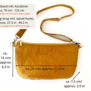 May include: A mustard yellow crossbody bag with a long adjustable strap. The bag measures approximately 11.4 inches wide and 6.3 inches tall. The strap is adjustable from 27.5 to 49.2 inches.