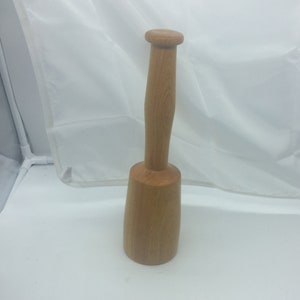 May include: A wooden mallet with a round head and a long handle. The mallet is made of light brown wood and has a smooth finish.