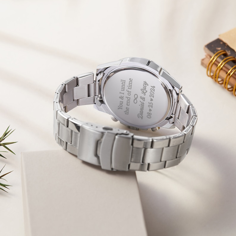 May include: Silver wristwatch with a stainless steel strap. The back of the watch has an engraved message: "You & I until the end of time, Daniel & Lucy 08.25.2024".