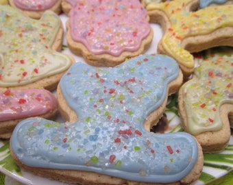 May include: A collection of shaped sugar cookies decorated with pastel-colored icing in shades of blue, pink, yellow, and light green. Each cookie is topped with a generous sprinkling of multicolored sugar crystals in red, green, and blue.