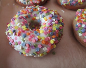 May include: A white frosted donut with colorful sprinkles. The donut is a classic treat with a sweet and sugary flavor.