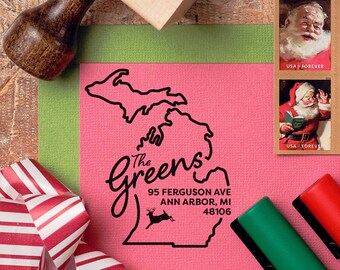 May include: A pink card with a black outline of the state of Michigan and the text "The Greens" in a cursive font. The address "95 Ferguson Ave Ann Arbor, MI 48106" is printed below the state outline. A small reindeer is printed below the address.