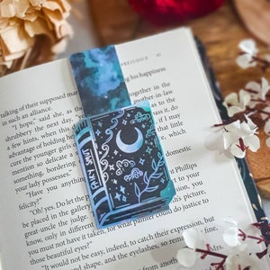 Peut inclure: Un marque-page bleu et noir avec un motif de lune et d'étoiles. Le marque-page porte l'inscription "Fairy Smut".