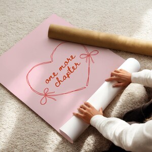 May include: A pink poster with a red heart outline and the words "one more chapter" in red script. A rolled-up white poster and a brown cardboard tube are also visible. The image is taken from an overhead perspective.