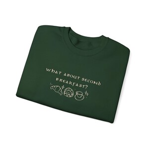 May include: A dark green t-shirt with the text "What about second breakfast?" in white with a small illustration of a croissant, a pastry, and a cup of coffee.
