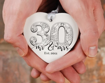 May include: White ceramic heart-shaped ornament with a black floral design and the text "30 mr & mrs Est. 2011".