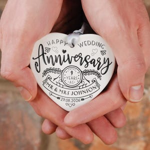 May include: White ceramic heart-shaped ornament with black text that reads "Happy Wedding Anniversary 9 Years -  Mr. & Mrs. Johnson 29.08.2026".