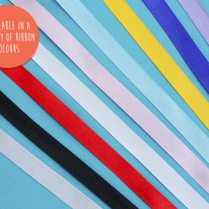May include: A variety of ribbon colours displayed on a blue background. The text "AVAILABLE IN A VARIETY OF RIBBON COLOURS" is written in a white circle on the top left of the image.