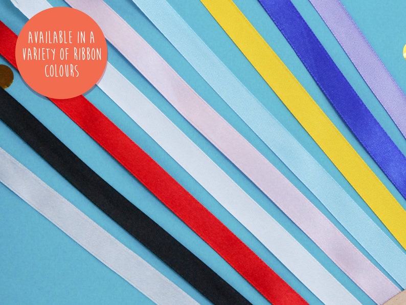 May include: A variety of ribbon colours displayed on a blue background. The text "AVAILABLE IN A VARIETY OF RIBBON COLOURS" is written in a white circle on the top left of the image.