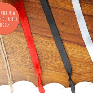 May include: A close-up of four different ribbon colors: red, black, white, and natural twine. The text "AVAILABLE IN A VARIETY OF RIBBON COLORS" is visible in the image.