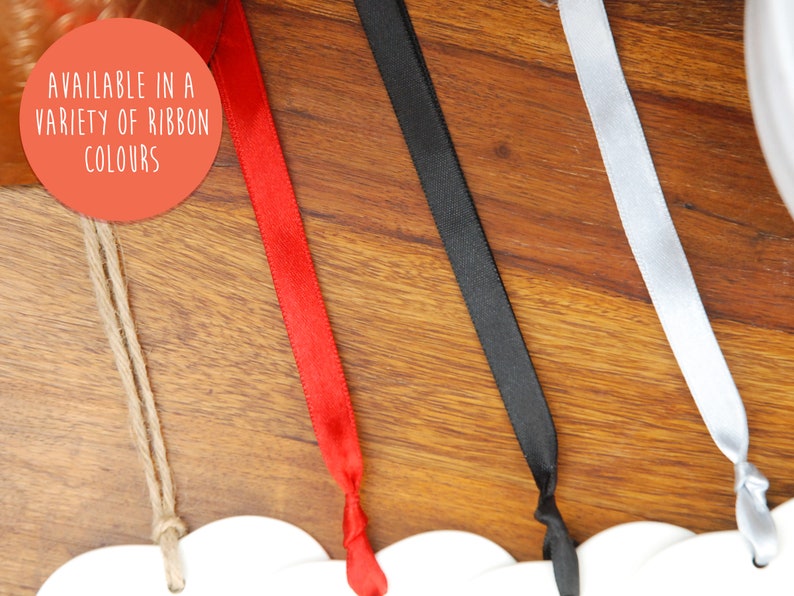 May include: A close-up of four different ribbon colors: red, black, white, and natural twine. The text "AVAILABLE IN A VARIETY OF RIBBON COLORS" is visible in the image.