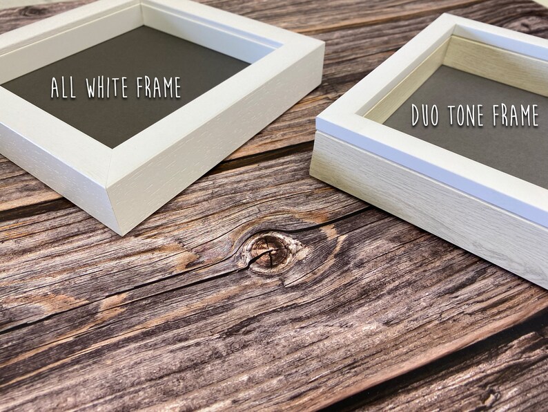 May include: Two picture frames, one white and one with a white border and a natural wood finish. The white frame says "ALL WHITE FRAME" and the other says "DUO TONE FRAME".