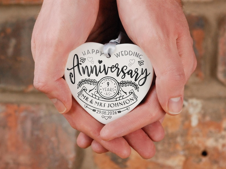 May include: White ceramic heart-shaped ornament with black text that reads "Happy Wedding Anniversary 9 Years -  Mr. & Mrs. Johnson 29.08.2026".