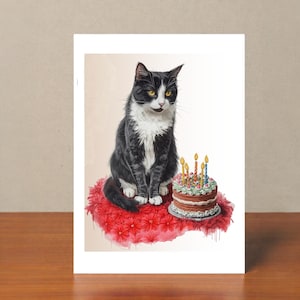 May include: A greeting card featuring a watercolor illustration of a black and white cat sitting on a red floral cushion. A chocolate cake with lit candles sits nearby. The cat has yellow eyes and is looking forward.