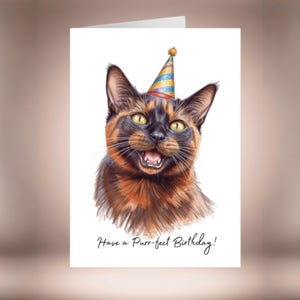 Può includere: Biglietto di auguri di compleanno con un gatto sorridente con un cappello da festa. Il gatto ha pelo nero e marrone e occhi gialli. Il testo "Have a Purr-fect Birthday!" è scritto sotto.