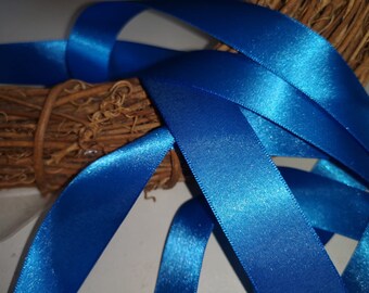 May include: A close-up of a bundle of blue satin ribbon. The ribbon is arranged in a criss-cross pattern, creating a textured look.