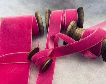 May include: Pink velvet ribbon spools on wooden spools. The ribbon is soft and luxurious, perfect for adding a touch of elegance to any project.