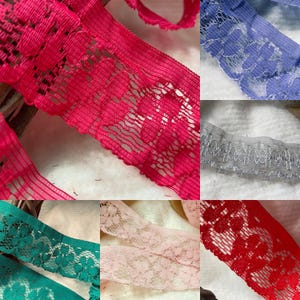 May include: A selection of colourful lace ribbons in pink, blue, grey, green, peach, and red. The lace features various floral and geometric patterns, with a delicate, open weave. Suitable for crafting and sewing projects.