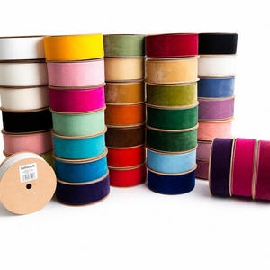 May include: A collection of velvet ribbon spools in a wide variety of colours including white, yellow, pink, red, black, green, blue, and purple. Each spool features a cardboard core with the Habicraft brand label visible on the front spool.