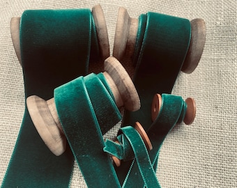 May include: Four spools of emerald green velvet ribbon. The ribbon is wound around wooden spools.