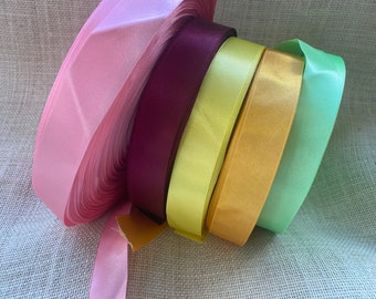 May include: Five spools of satin ribbon in various colors: light pink, burgundy, light yellow, gold, and light green.