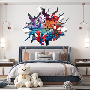 May include: A wall decal featuring several Spider-Man characters bursting through a brick wall. The characters are in various poses, with vibrant red, blue, and black costumes. The scene is set in a bedroom with a bed, teddy bears, and a striped rug.