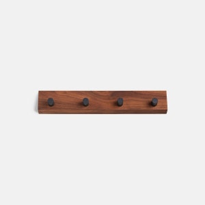 Könnte beinhalten: Ein Wand-Schlüsselhalter aus Holz mit vier schwarzen Metallhaken. Der Halter ist aus dunkelbraunem Holz.