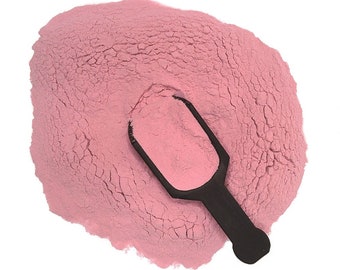 May include: A pink powder with a black scoop. The powder is in a pile and the scoop is lying on top of it.