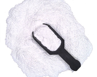 May include: A white powder with a black plastic scoop. The powder is piled high and the scoop is partially buried in the powder.