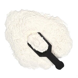 May include: A pile of white powder with a black scoop. The powder appears to be flour or a similar fine-grained substance. The scoop is filled with the powder, suggesting a measurement or portioning of the product. The image is shot from a top-down perspective.