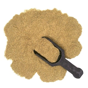 May include: A close-up of a pile of dried parsley powder with a small black scoop. The powder is a light green colour and has a fine texture.