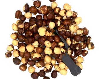May include: A pile of roasted hazelnuts, some with their skins on and some with their skins off, on a white background.