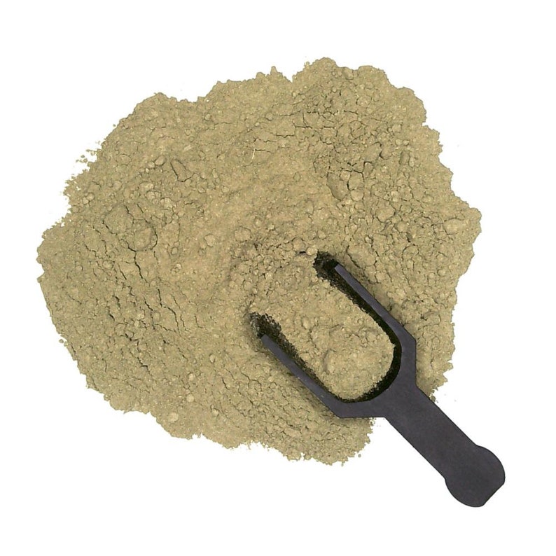 May include: A scoop of green powder on a white background. The powder is in a pile and a black plastic scoop is partially buried in the powder.